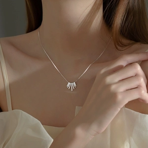 Minimalist silver fan-shaped fringe pendant necklace on a model wearing cream top