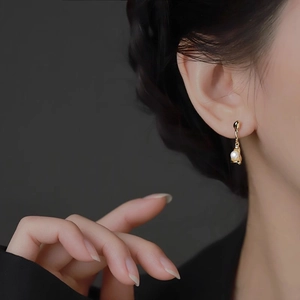 Elegant gold drop earrings with irregular pearl pendants shown on a model model