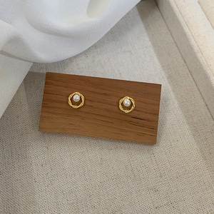 Boucles d'oreilles créoles dorées torsadées avec perle sur support en bois