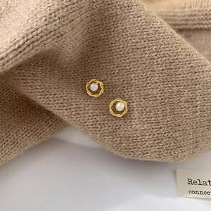 Détails macro des boucles d'oreilles créoles torsadées dorées avec perles blanches