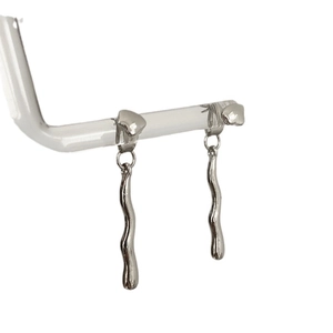 Irregular silver liquid metal wavy drop earrings displayed on a minimalist clear stand