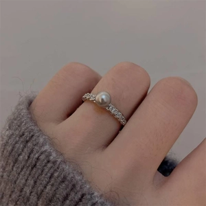 Exquisite pearl ring with silver band and side diamonds worn on a finger