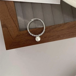 Detail of silver twisted band ring with a lustrous white pearl on a wooden jewelry tray