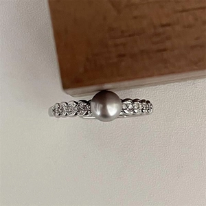 Macro shot of an elegant grey pearl ring with sparkling pavé diamonds on a silver band