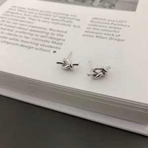 Minimalist 925 sterling silver knotted stud earrings on a white aesthetic magazine