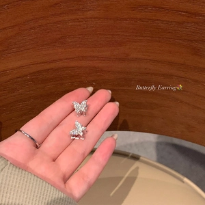 Close-up of sparkling silver butterfly earrings with micro-set stones and hollow design