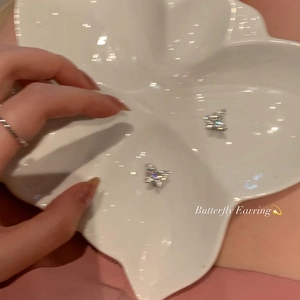 Sparkling crystal butterfly stud earrings with hollow design on a white petal tray