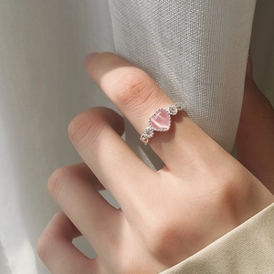 Pink heart cat eye stone ring with silver band and side carvings on female finger