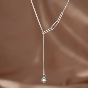 Close-up of asymmetric silver Y-shaped tassel necklace with ball pendant on silk
