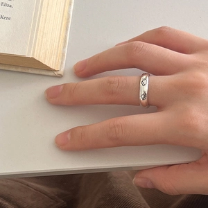 Detail showing hand-painted sun and cloud engravings on a sleek silver minimalist ring
