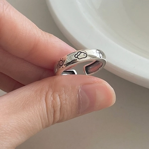 Macro detail of silver adjustable ring featuring engraved sun and cloud weather patterns