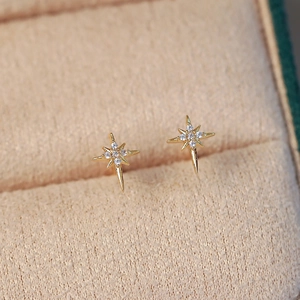 Minimalist gold starburst stud earrings featuring white cubic zirconia accents
