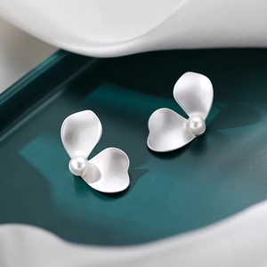 Elegant S925 silver matte petal stud earrings with white pearls on green display tray
