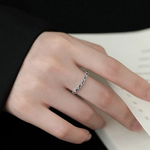 Detailed macro of a wavy silver ring set with colorful zircon stones on a model's finger