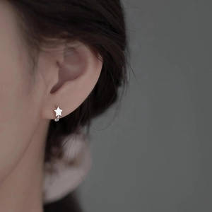 Gros plan d'une boucle d'oreille étoile en argent minimaliste portée par un mannequin
