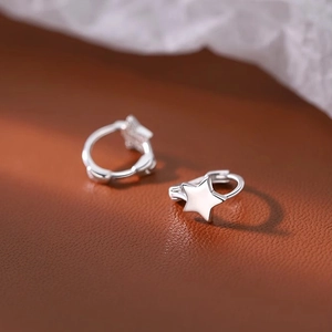 Vue macro de boucles d'oreilles étoiles en argent S925 sur une texture cuir sombre