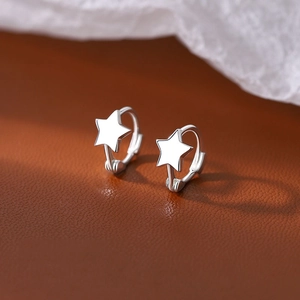 Boucles d'oreilles créoles étoiles en argent S925 sur fond en cuir texturé élégant