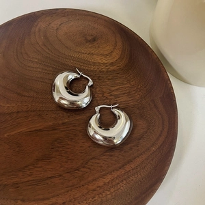 Chic silver polished crescent hoop earrings on a vintage wooden tray setup