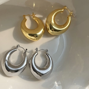 Macro detail of chunky oval hoop earrings in polished gold and silver finishes