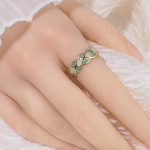 Detail of French style gold lattice ring with green and white enamel on a silk background