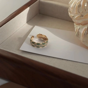 Detail of green and white enamel argyle pattern on wave-edged golden open ring