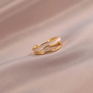 Detail of a wavy double-layered gold ring with elegant white enamel finish on satin