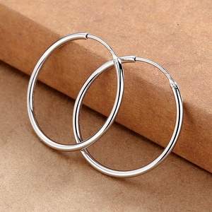 Macro shot of polished silver hoop earrings resting on a brown paper package