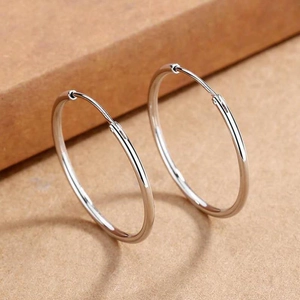 Detailed view of large silver hoop earrings with a polished mirror finish and latch closure