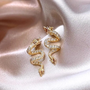Detailed macro view of gold dragon stud earrings with sparkling white cubic zirconia