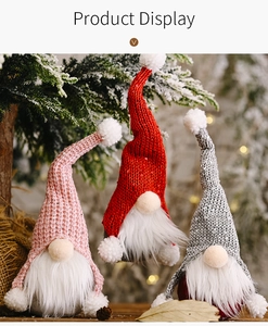 Close-up of three plush Christmas gnomes with sequins and faux fur on snowy pine branches
