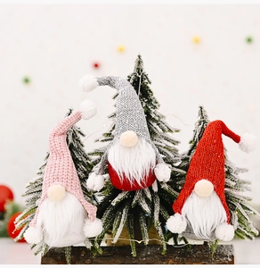 Close-up of three knitted Christmas gnomes with long white beards on snowy wood