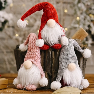 Drei Weihnachtswichtel mit Pailletten-Strickmützen in Rot, Rosa und Grau auf Holzstümpfen