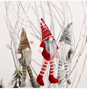 Three Christmas gnomes with striped hats and long legs hanging on white winter branches