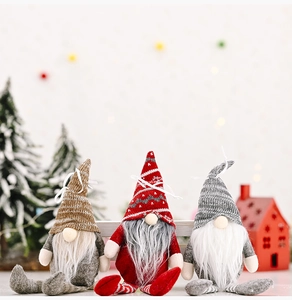 Three striped Christmas gnomes with pointed hats sitting by a mini tree and red wooden house