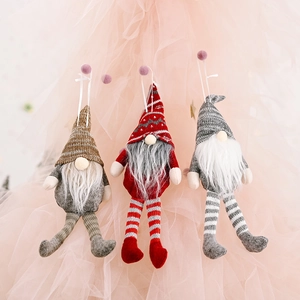 Three Christmas gnomes with striped legs and long hats hanging on a pink backdrop