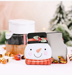 Macro shot of snowman-shaped tin box for Christmas candies with festive winter background