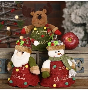 Three-piece Christmas plush doll set with Santa, snowman and reindeer on a wooden cabinet