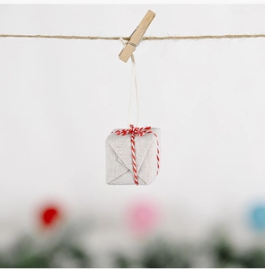 Detail of burlap mini gift box ornament with red cotton twine and wooden clip