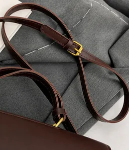 Détail de la bandoulière réglable en cuir marron foncé avec boucle en métal doré