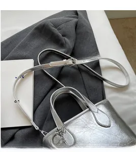 Detail view of silver metallic bucket bag with adjustable strap and ring charm