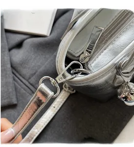Close-up of shiny silver metallic hardware buckle and zipper on the bucket bag