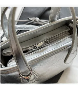 Close-up of smooth metal zipper and silver wrinkled texture on minimalist bucket bag