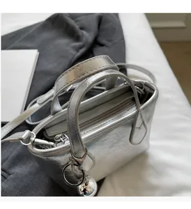 Top view of a silver metallic tote bag with wrinkled texture and spherical metal charm