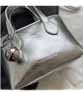 Detail of silver textured bucket bag with metal ball charm and embossed fashion text