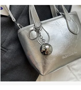 Detail of silver metallic bucket bag with pleated texture and round charm accent