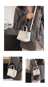 Detail of white PU leather bucket bag featuring silver ball charm and adjustable strap