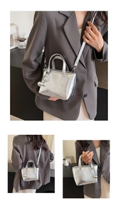 Close-up of metallic silver bucket bag with pleated texture and stylish spherical charm
