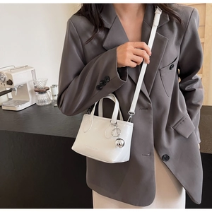 Close-up of white fashion bucket bag with silver ball charm and textured finish