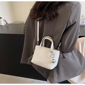 Detailed back view of a white leather bucket bag with silver metal ball and shoulder strap