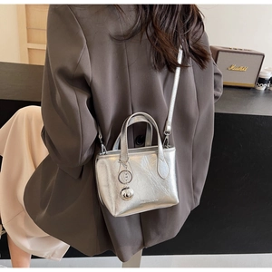 Macro detail of silver textured PU leather bucket bag with metallic ball charm and engraving